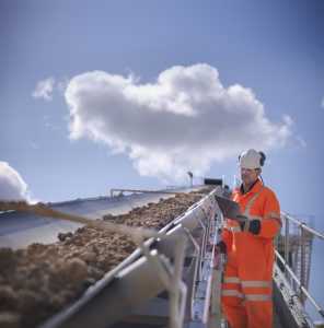 Worker inspecting stone screening and crushing machine in quarry